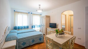 A compact room with a bed, a small table with a fruit basket, a TV, and a wardrobe. - 1 bedroom gorgeous apartment in Orosei (Orosei)