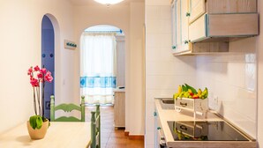 A kitchen with wooden cabinets, a countertop with a fruit basket, and a potted plant on the table. - 1 bedroom gorgeous apartment in Orosei (Orosei)