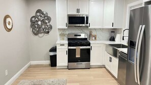 A modern kitchen with white cabinetry, a stainless steel refrigerator, a microwave, and a stove. - El Cajon 2BR 1BA Back Unit | Near Zoo and DT SD (El Cajon)