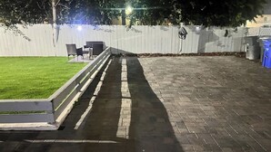 Un espace extérieur aménagé avec un revêtement pavé, une clôture blanche, une pelouse et du mobilier de jardin.