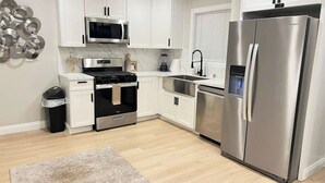 Une cuisine moderne avec des meubles blancs, un réfrigérateur en acier inoxydable, un four à micro-ondes, une cuisinière et un évier.