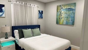 Une chambre à coucher avec un lit, une table de chevet et un tableau accroché au mur.