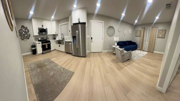 Une cuisine moderne avec des meubles blancs, des appareils en acier inoxydable et un tapis gris.