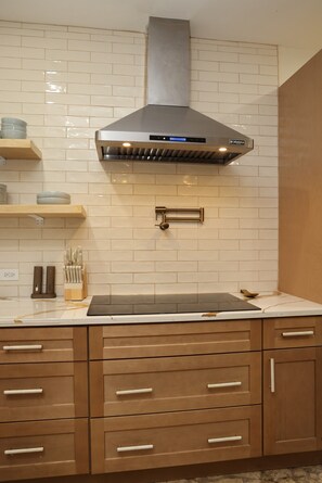 A kitchen with a stainless steel range hood, wooden cabinets, and a tiled backsplash. - Ocean-View 2BR + Soaking Pool · Christiansted (Christiansted)