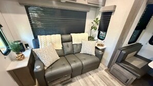 Interior compacto de autocaravana con sofá, una mesita y ventana.