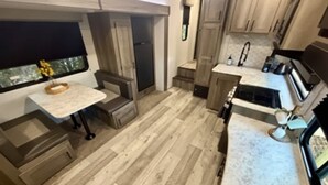 Una cocina funcional con piso de madera, encimera y alacenas.