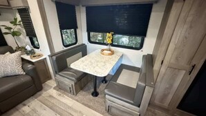 Interior de una autocaravana compacta, con cocina americana, zona de estar y ventanas.