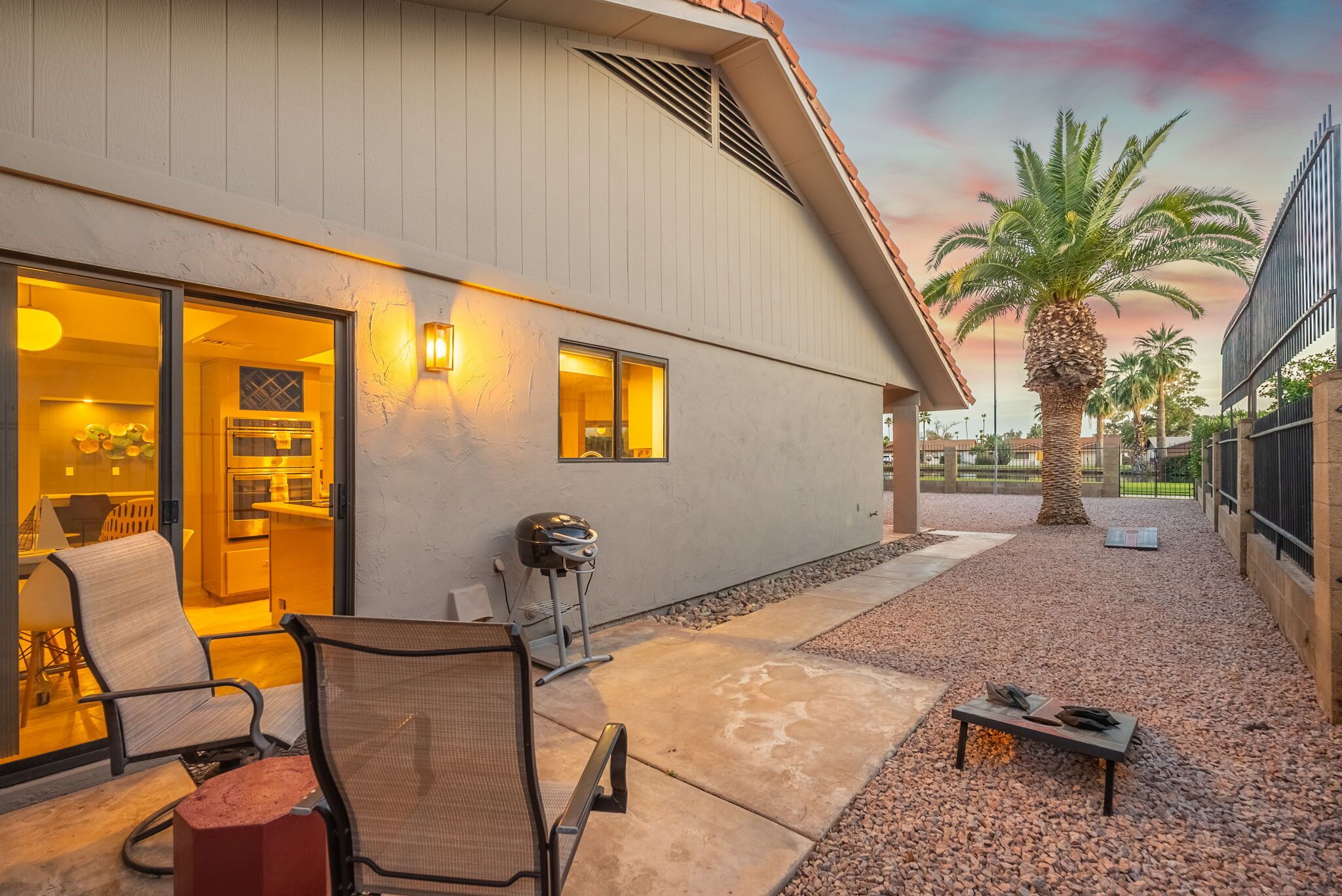 A modern house with a patio area featuring outdoor seating and a grill.