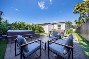 A backyard with a hot tub, outdoor seating, and a barbecue area.
