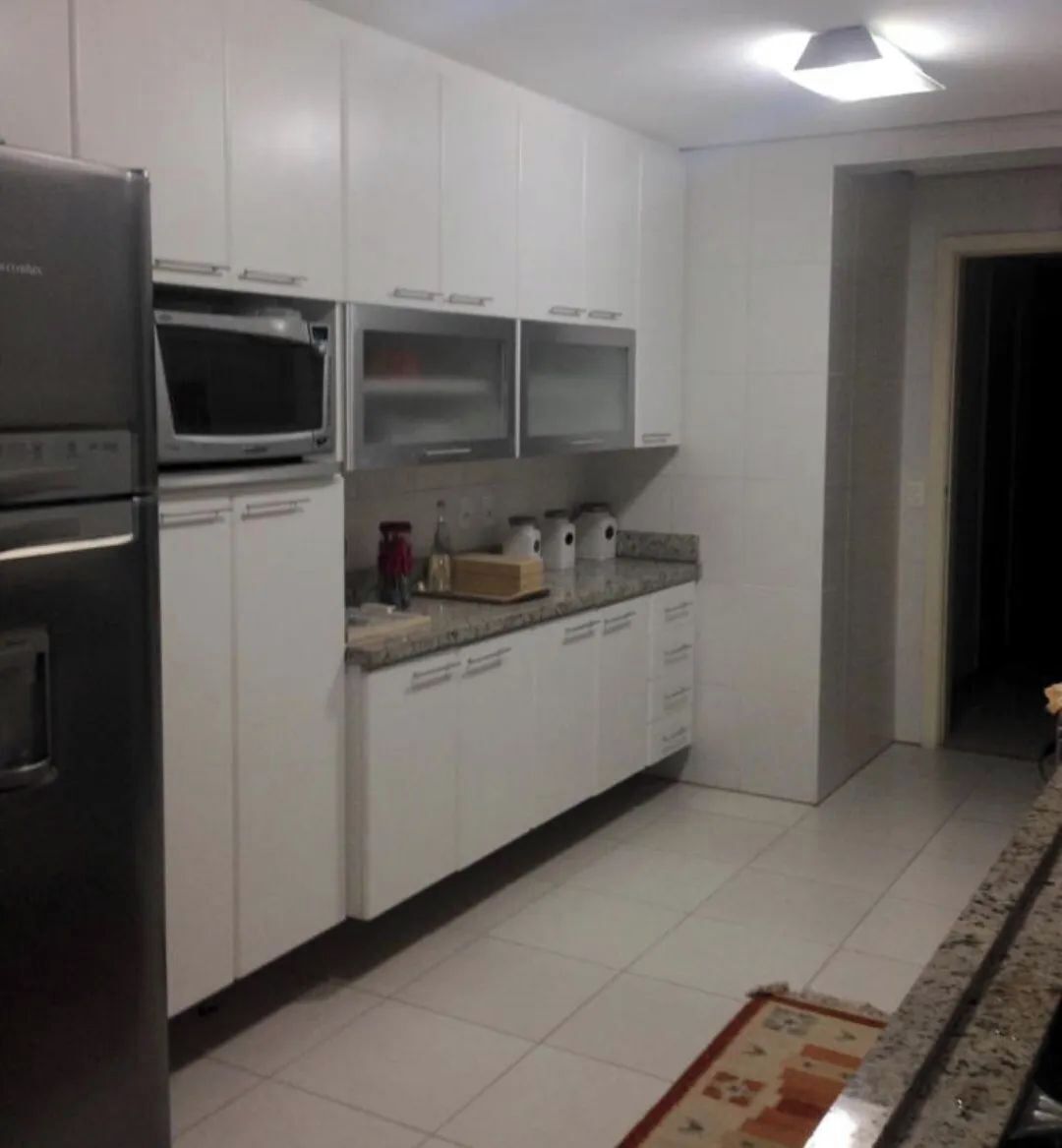 A kitchen with white cabinets, a microwave, a toaster, and a sink.