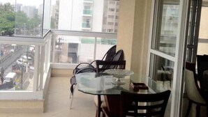 Un balcone con tavolo e sedie in vetro, vista sulla città.