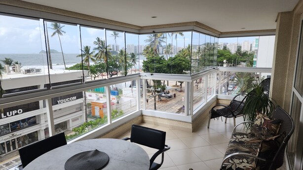 Un balcone con vista sulla spiaggia e sullo skyline cittadino, con un tavolo rotondo e sedie, e un divano in vimini.