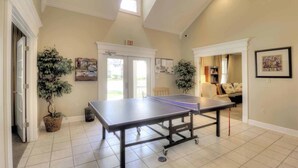 Un'ampia stanza con un tavolo da ping pong, una porta con la scritta 