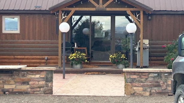 A log cabin with a welcoming entrance, stone steps, and potted plants. - Amazing Country Farm in charming Del Norte perfect for large groups and families (Del Norte)