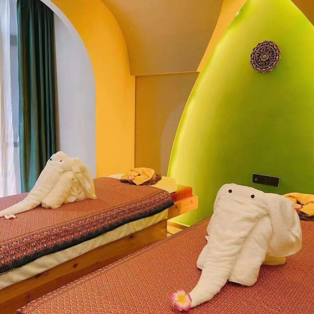 A room with two beds, a green wall, and a small decorative item on the wall.