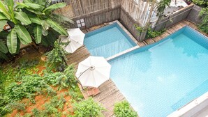 A rectangular swimming pool with a wooden deck and two white umbrellas. - Morning Sun Hotel (Guilin)