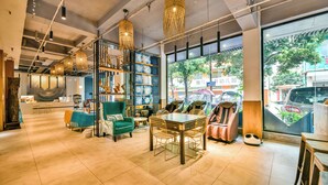 A modern interior with a dining area, seating, and large windows offering a view of the street. - Morning Sun Hotel (Guilin)