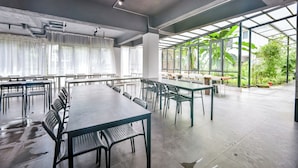 A spacious conference room with long tables and chairs, large windows, and a view of greenery outside. - Morning Sun Hotel (Guilin)