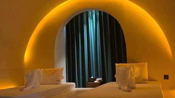 A room with two beds, a large window with curtains, and a warm yellow lighting. - Morning Sun Hotel (Guilin)