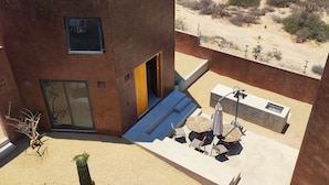 A modern building with a flat roof, a small patio area with outdoor seating, and a cactus in the foreground. - Ideal cottage to rest with the family very close to the sea, one pet is accepted. (El Sargento)