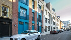 Uma fileira de edifícios modernos e com vários andares, com um carro branco estacionado na rua.