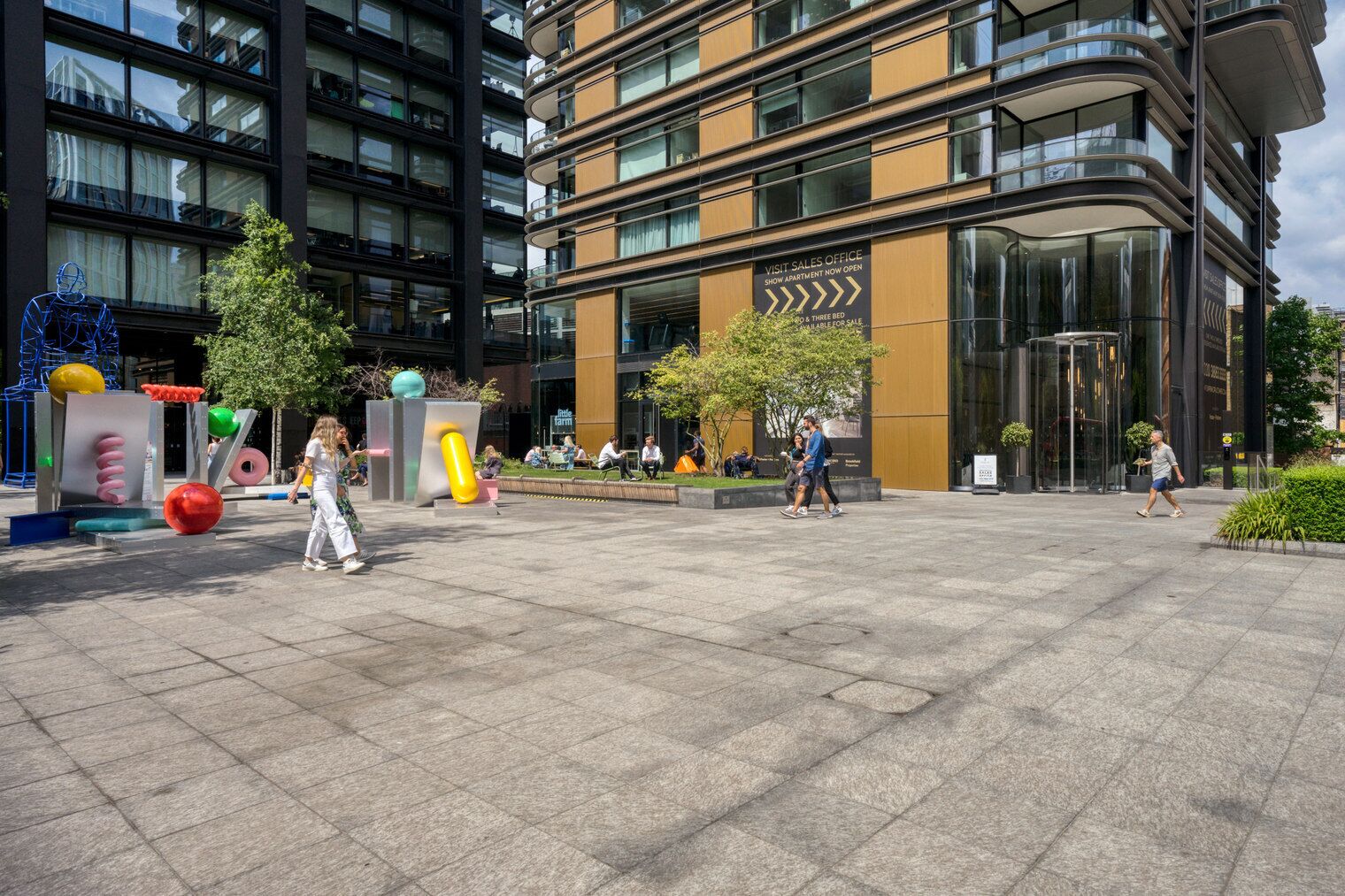 Un hôtel moderne doté d’une façade en verre, d’un hall d’entrée spacieux et d’une enseigne indiquant un bureau de vente.