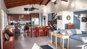 A spacious living area with a kitchen, dining table, and a staircase leading to another level. - Brisas de Ballena with Panoramic Ocean View (Uvita)