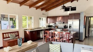 A spacious kitchen with wooden cabinets, a central island, and modern appliances. - Brisas de Ballena with Panoramic Ocean View (Uvita)