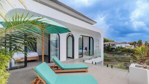 Eine moderne Lounge-Bereich im Freien mit zwei Holzliegen und einem grünen Sonnenschirm.