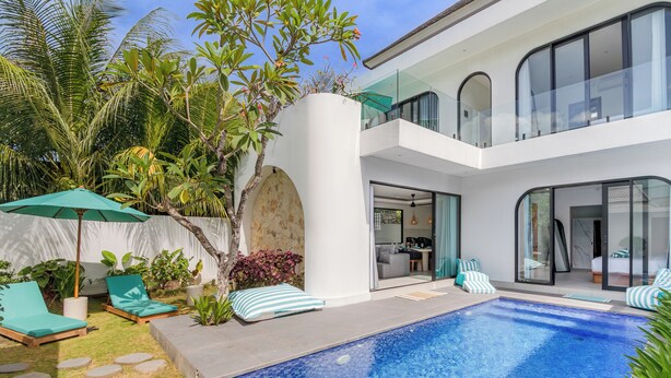 Ein modernes Haus mit Swimmingpool, Sitzgelegenheit im Freien und üppiger Bepflanzung.