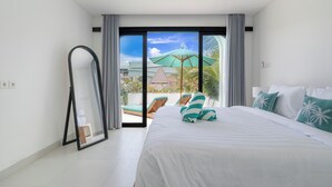 Ein Hotelzimmer mit einem großen Bett, einem Spiegel und Blick auf einen Pool und Palmen.