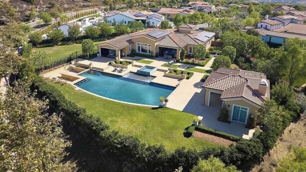 A residential area with multiple houses, a large swimming pool, and a mountain in the background.