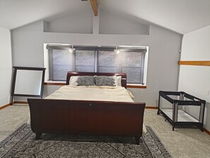 Ein Schlafzimmer mit einem großen Bett, einem Fenster mit Jalousien, einer Stehlampe und einem kleinen Tisch.