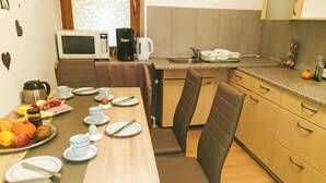 A kitchen with a wooden table set for breakfast, a microwave, coffee maker, and a sink.