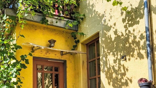 A yellow building with a brown door, stone steps, and a window.