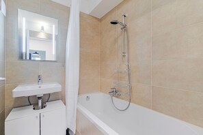 Een badkamer met een wit wastafelmeubel, spiegel en douche.