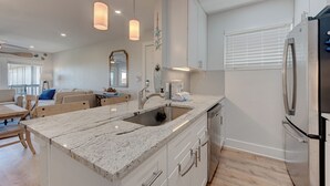 A modern kitchen with a marble countertop, stainless steel appliances, and pendant lighting.