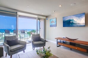 A modern living room with two armchairs, a wooden console table, and a large ocean wave painting. - 3 Ocean Front Units * 3 Patios * 2 Levels (San Diego)