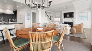 Een eetgedeelte met een ronde houten tafel, rieten stoelen en een kroonluchter.
