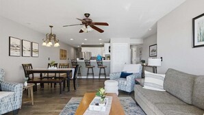 Uma sala de estar moderna com um sofá, uma mesa de centro e um espaço de refeições com cadeiras e uma mesa.