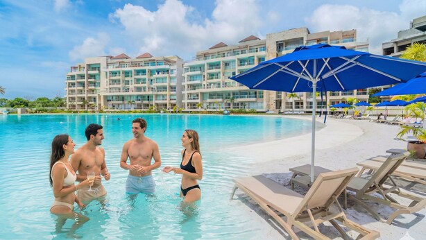 Ein Poolbereich mit Liegestühlen und Sonnenschirmen, umgeben von Hotelgebäuden.