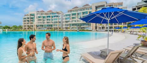 A swimming pool area with lounge chairs and umbrellas, surrounded by hotel buildings.