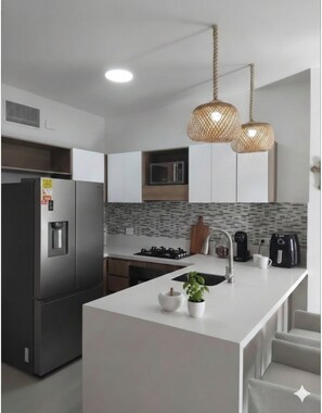 Uma cozinha moderna com uma ilha central, eletrodomésticos de aço inoxidável e um pendente.