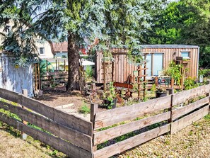A rustic wooden structure with a garden area, a wooden fence, and a shed with a blue door. - Tiny House Cottage Herbert by Interhome (Grossschönau)