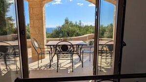 A patio with a table and chairs, a stone pillar, and a view of the landscape.