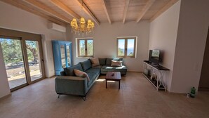 A spacious living room with a sectional sofa, a coffee table, a TV on a stand, and a chandelier.