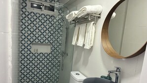 Pieni kylpyhuone, jossa on wc, suihku ja peilillä varustettu pesuallas.