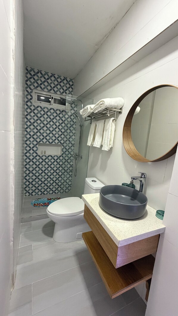 A compact bathroom with a toilet, a shower, and a sink with a mirror.