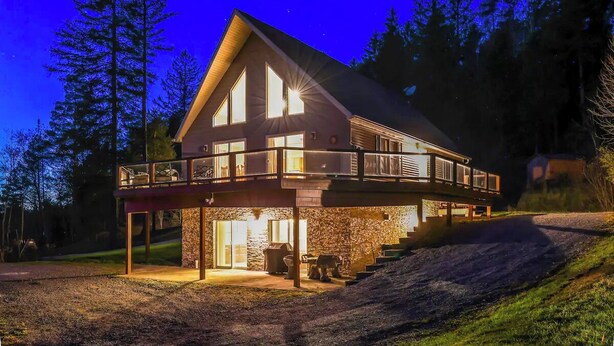 Une maison à deux étages dotée d’un balcon, de fondations en pierre et d’une allée menant à l’entrée.