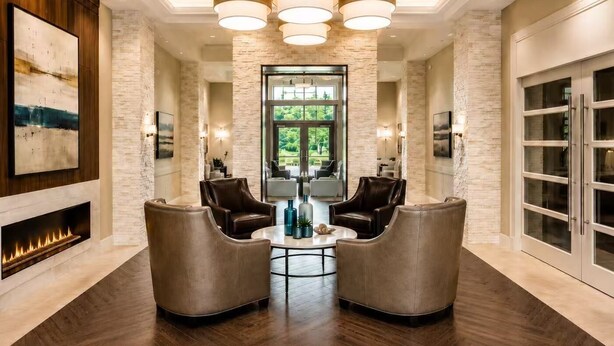 A modern lobby with a fireplace, leather armchairs, a round coffee table, and a large window offering a view of greenery. - New 2025 Beach Home! Ocean View Beach Club! 5 Minutes to Bethany Beach (Ocean View)